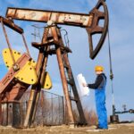 Petroleum engineer controlling work of oil well pump jack.