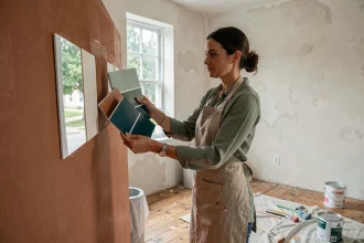 Femme comparant des échantillons de couleurs terracotta et bleu sarcelle dans un salon en cours de rénovation